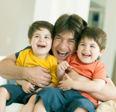 Padre con sus dos hijos abrazados y sonriendo