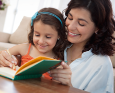 Mujer y niña leyendo juntas sonriendo