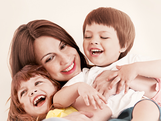 mujer abranzando y sonriendo con sus hijos