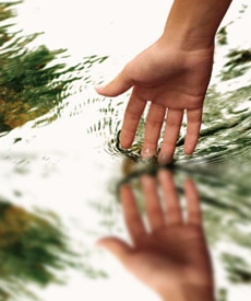 Mano de una mujer tocando muy suavemente agua.