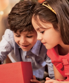 Dos niños observando un regalo, sonrien