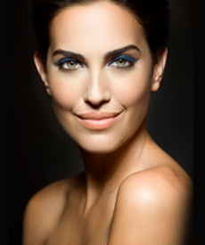 Mujer maquillada, tiene sus ojos iluminados, sonríe.